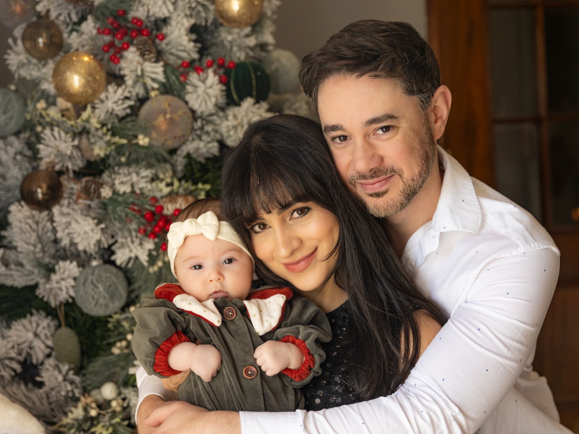 Família com bebé junto à árvore de Natal decorada