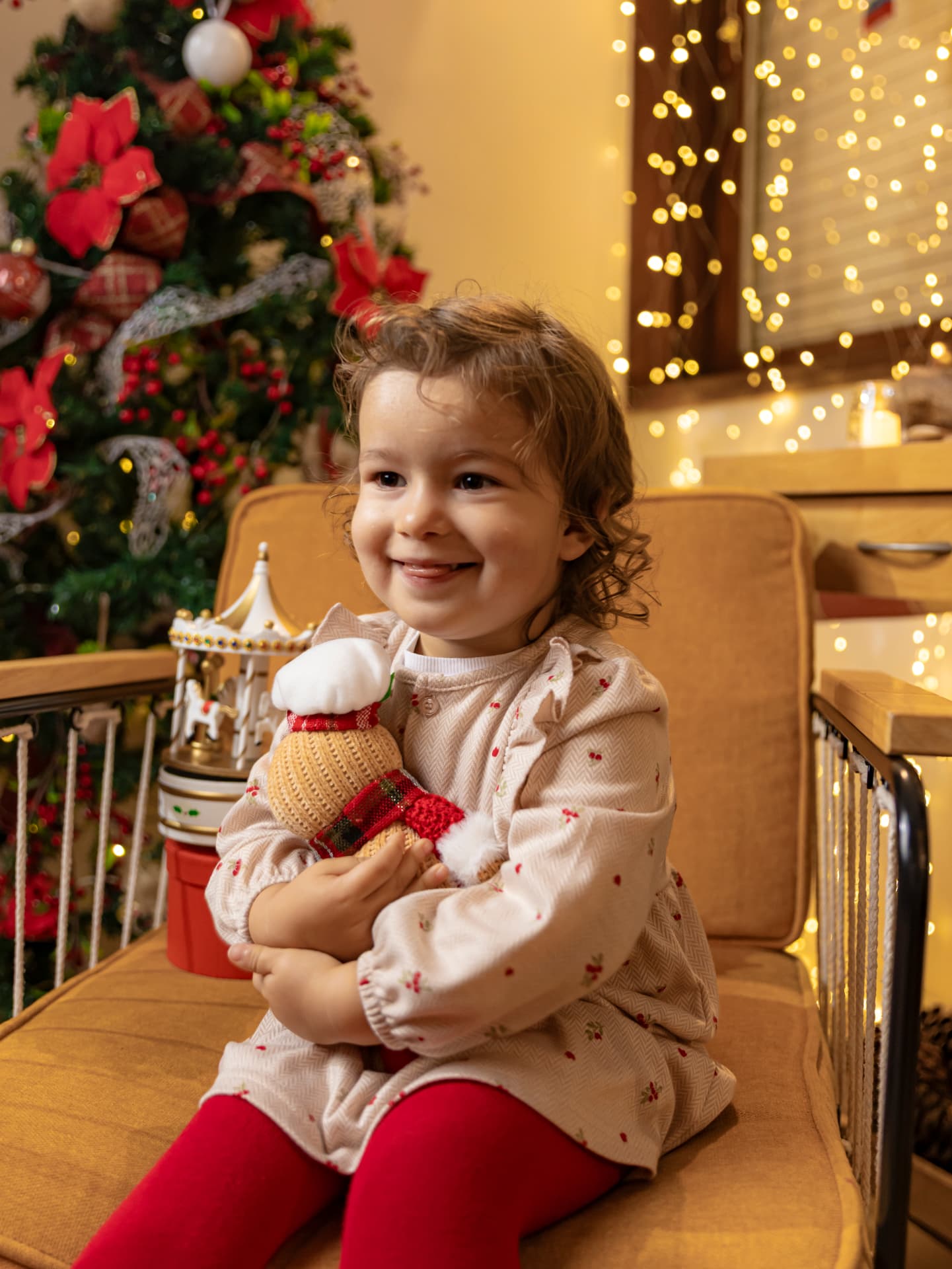 Menina a abraçar um boneco de neve junto à árvore de Natal