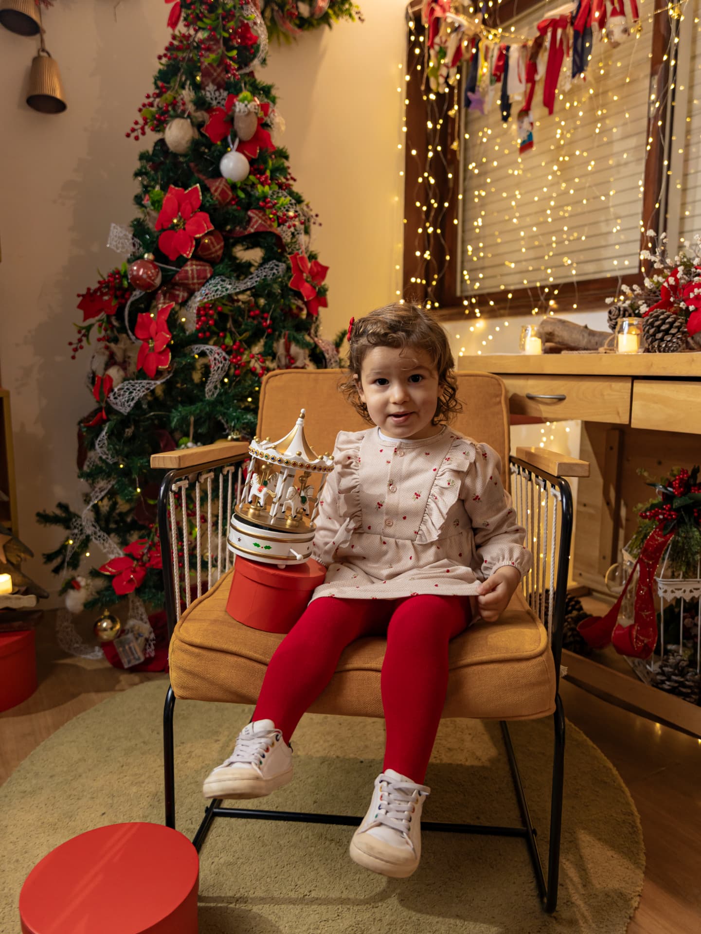 Menina sentada junto à árvore de Natal
