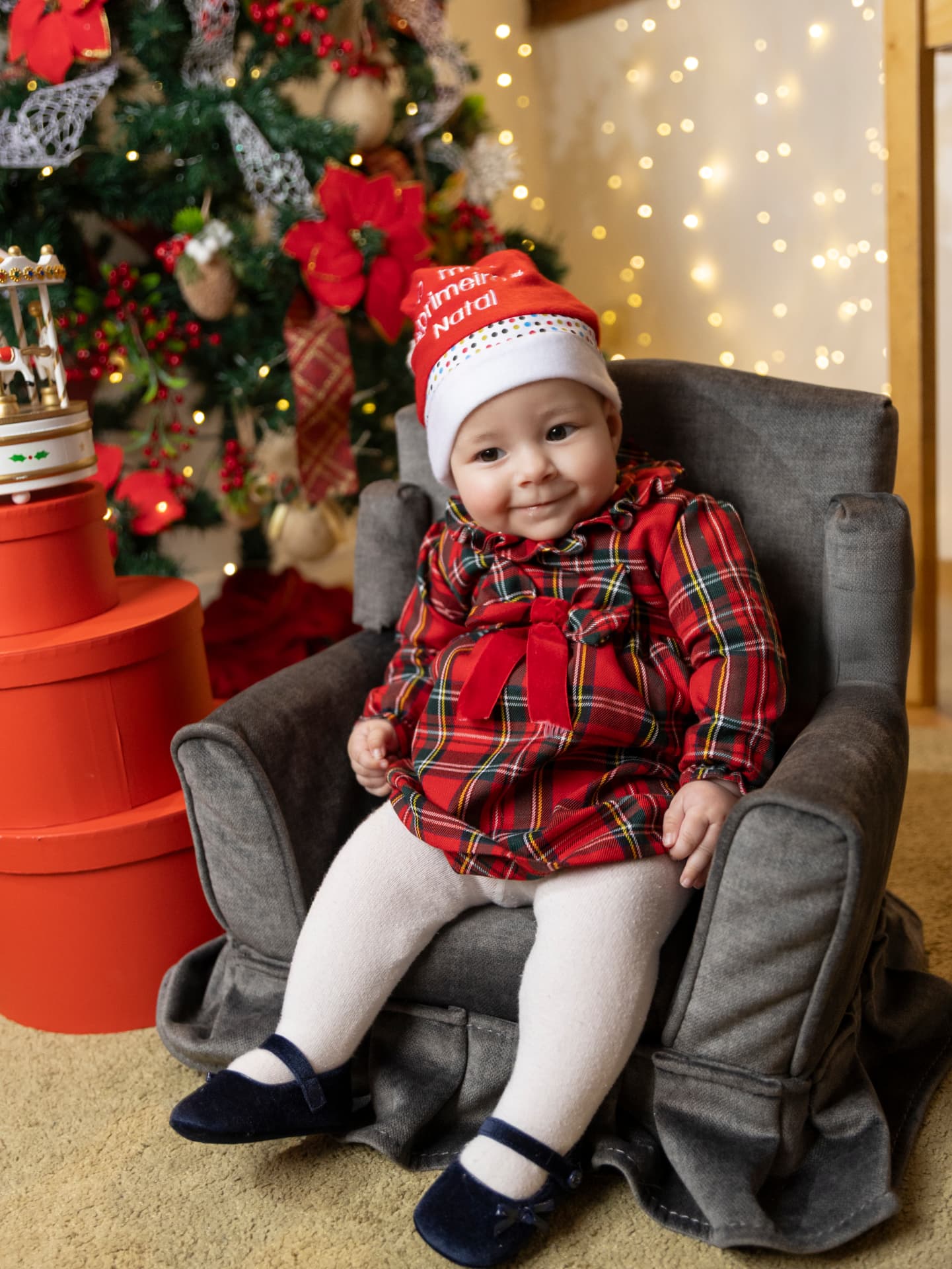 Bebé com gorro de Natal sentado numa poltrona