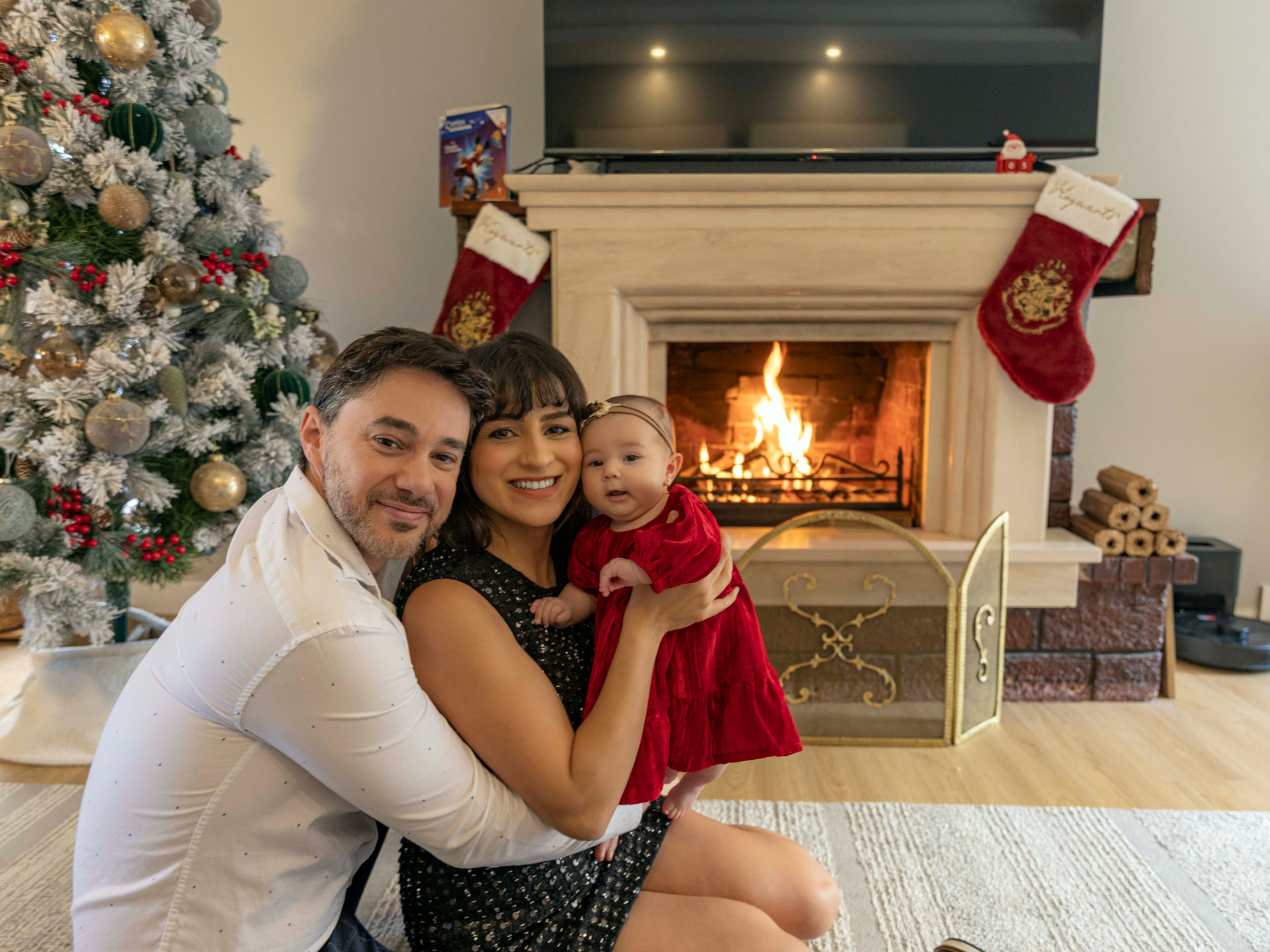 Família abraçada junto à lareira acesa e à árvore de Natal, numa sessão de Natal de anos anteriores